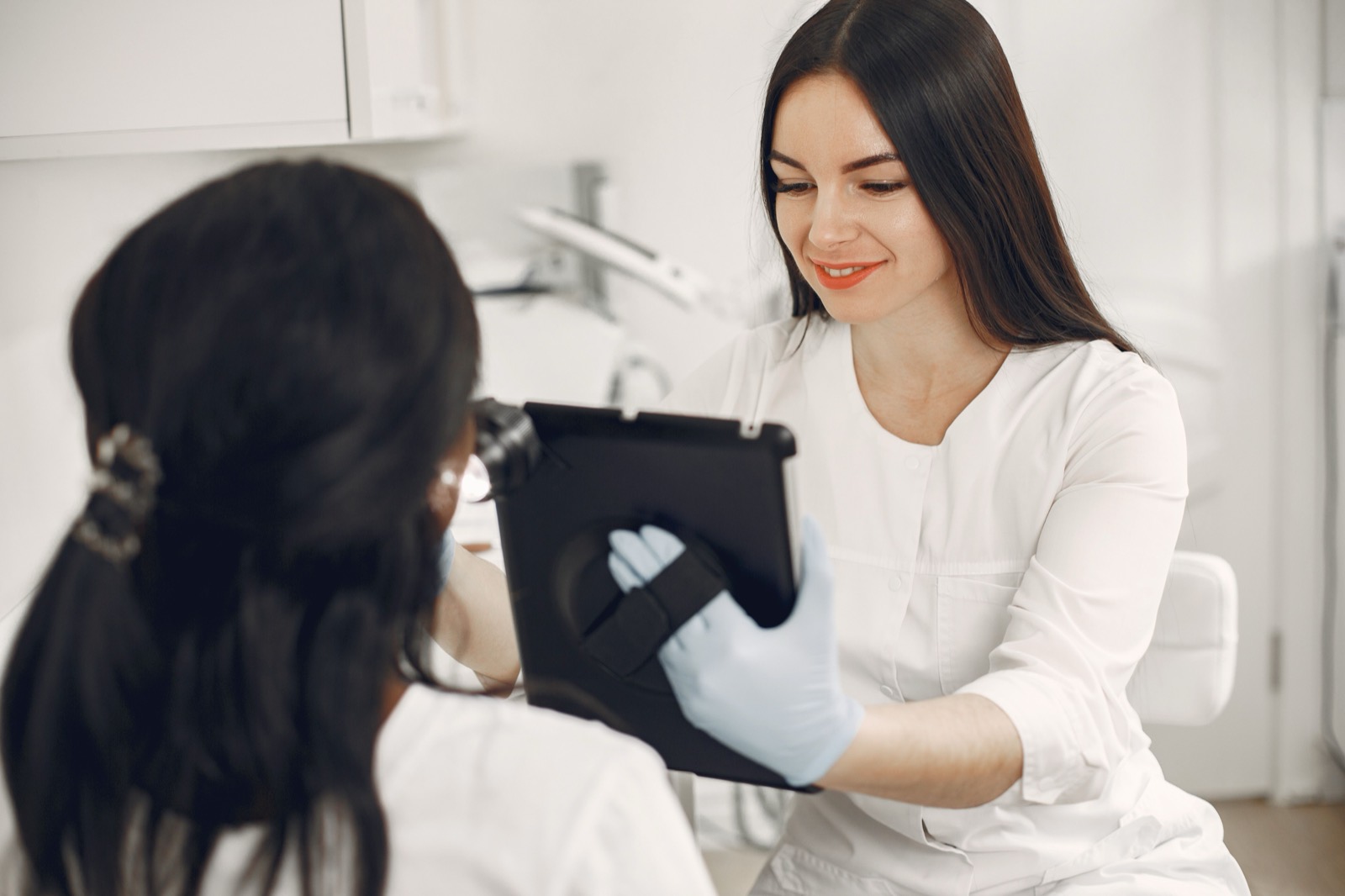 Esteticista sorrindo enquanto mostra informações num tablet para a cliente antes do atendimento