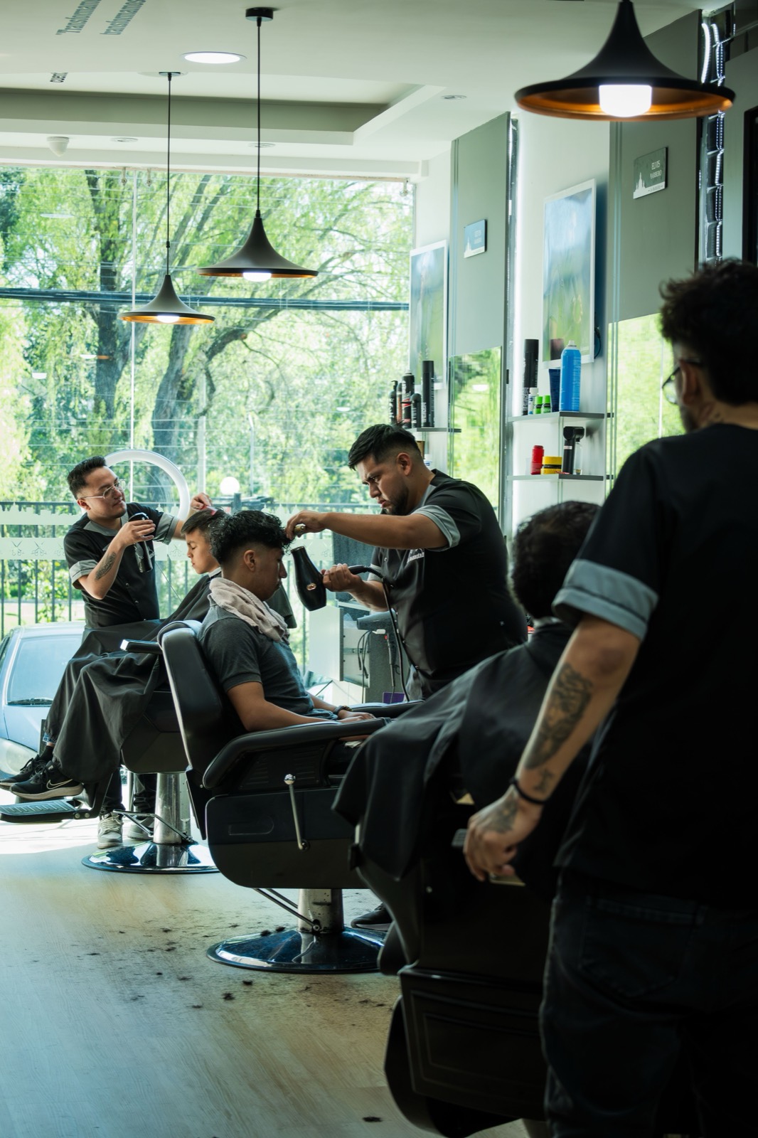 Barbeiros atendendo lado a lado numa barbearia movimentada